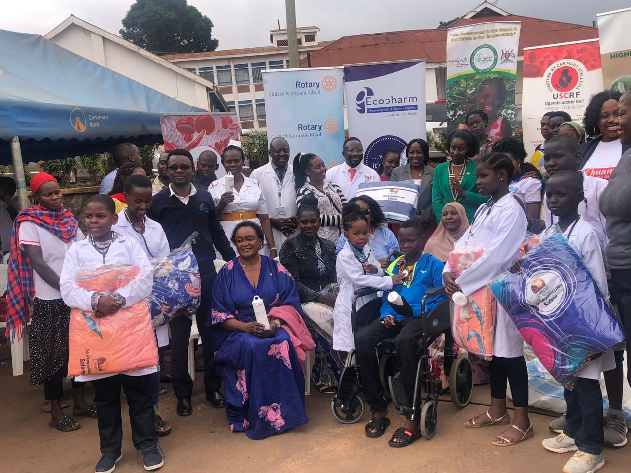 Participants and health organization representatives gather beneath outreach banners at an outdoor event.